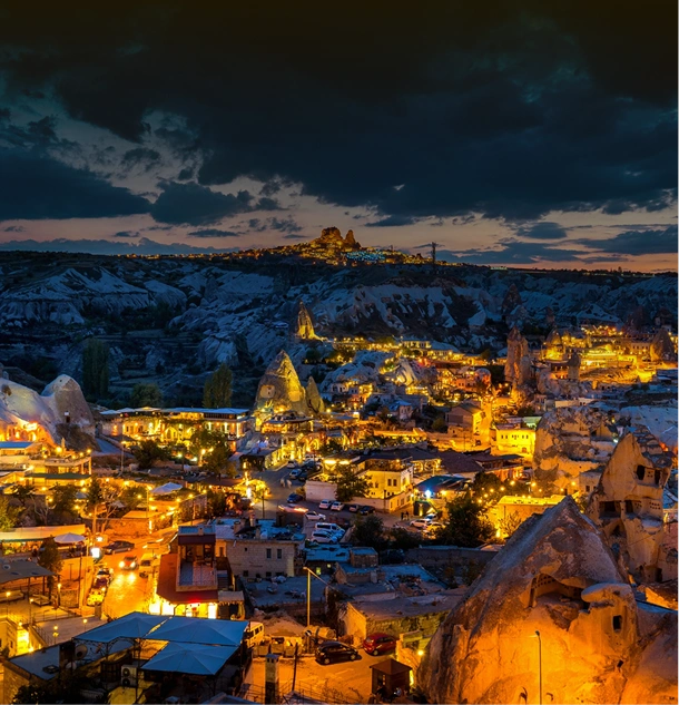 Göreme, Cappadocia at twilight with golden city lights.