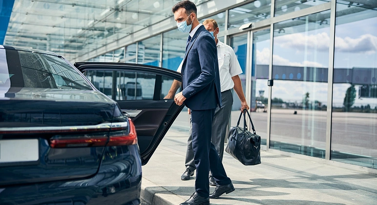Business traveler entering airport transfer car