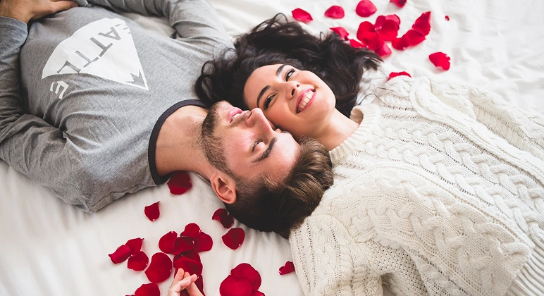Couple lying on bed with red rose petals