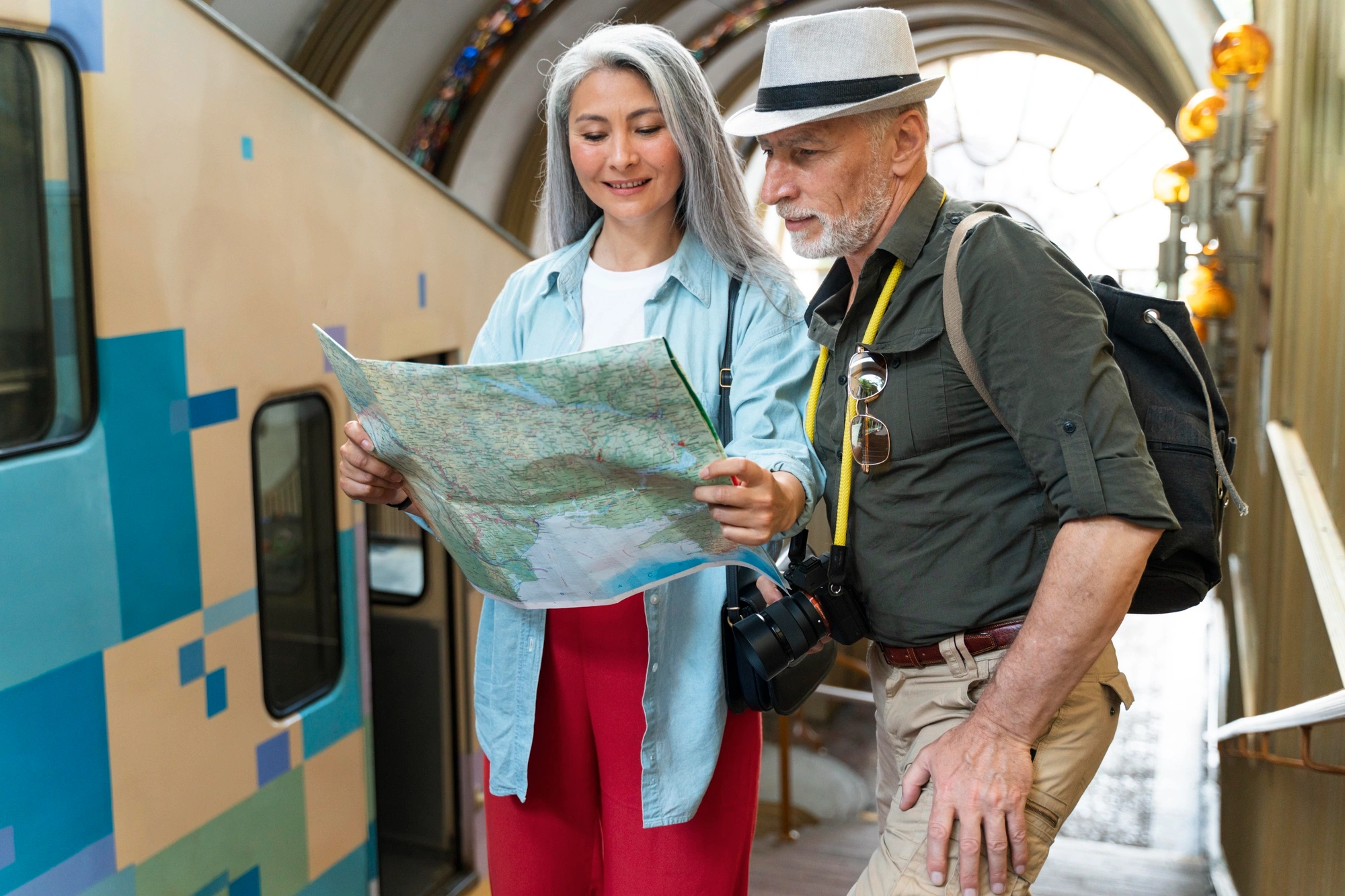 Senior couple with backpacks using a travel map