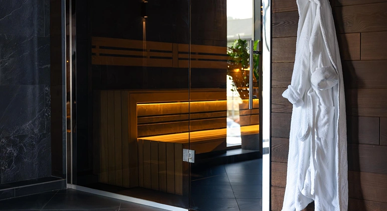 Modern sauna with glass door and warm lighting